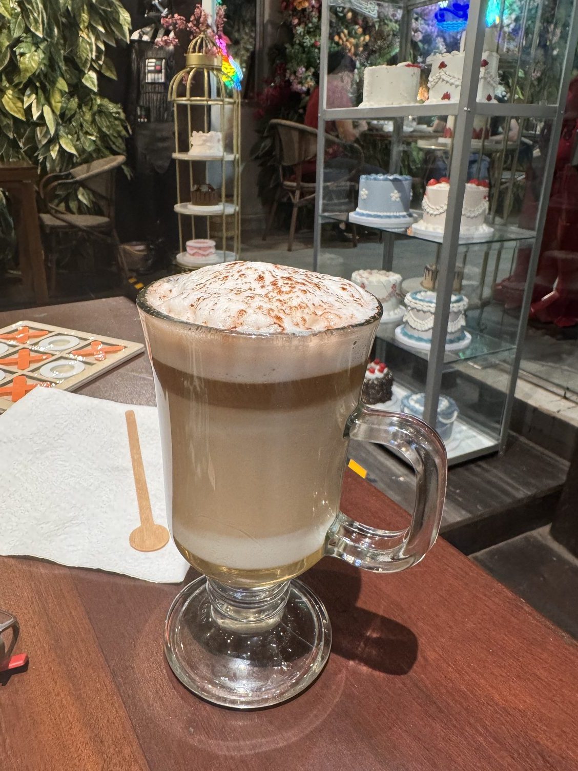 A tall foam drink in front of the cake case