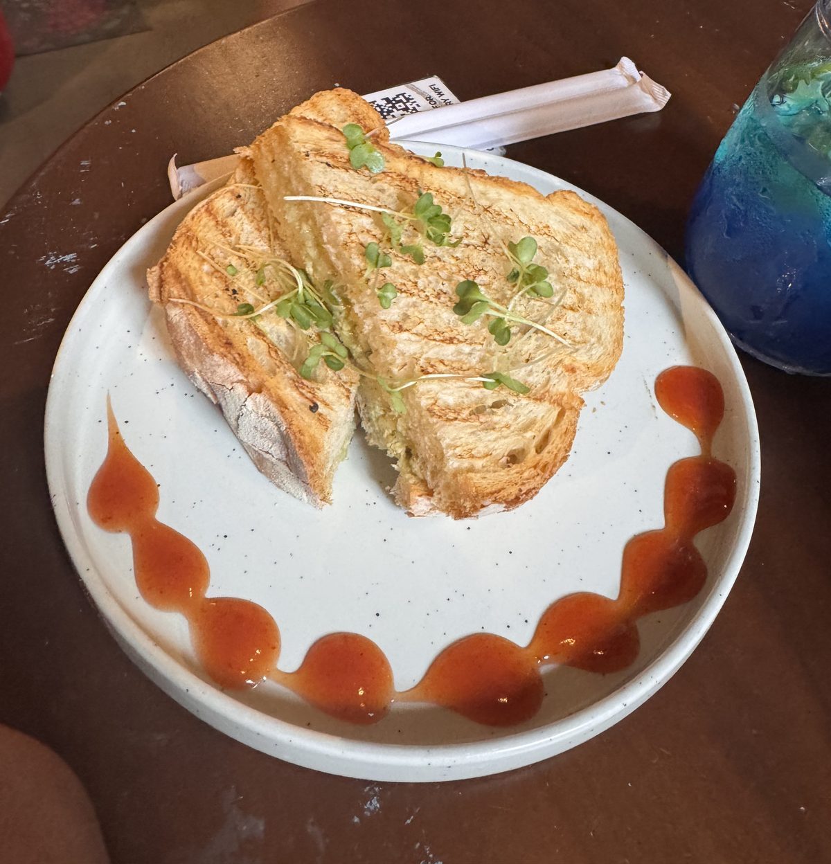 A toasted sandwich with greens and a sauce swirl